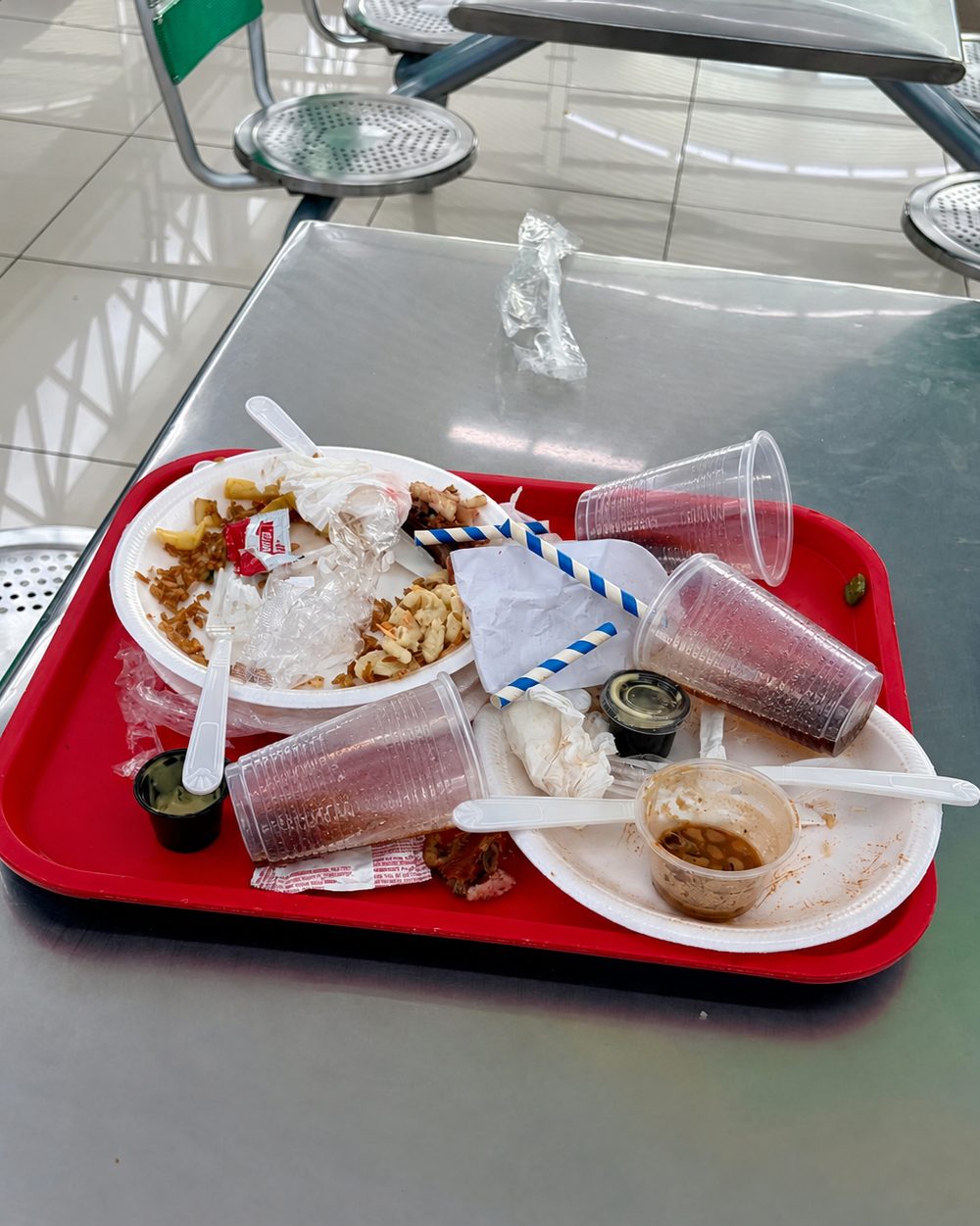 Bandeja de comida rápida con platos y vasos descartables sucios